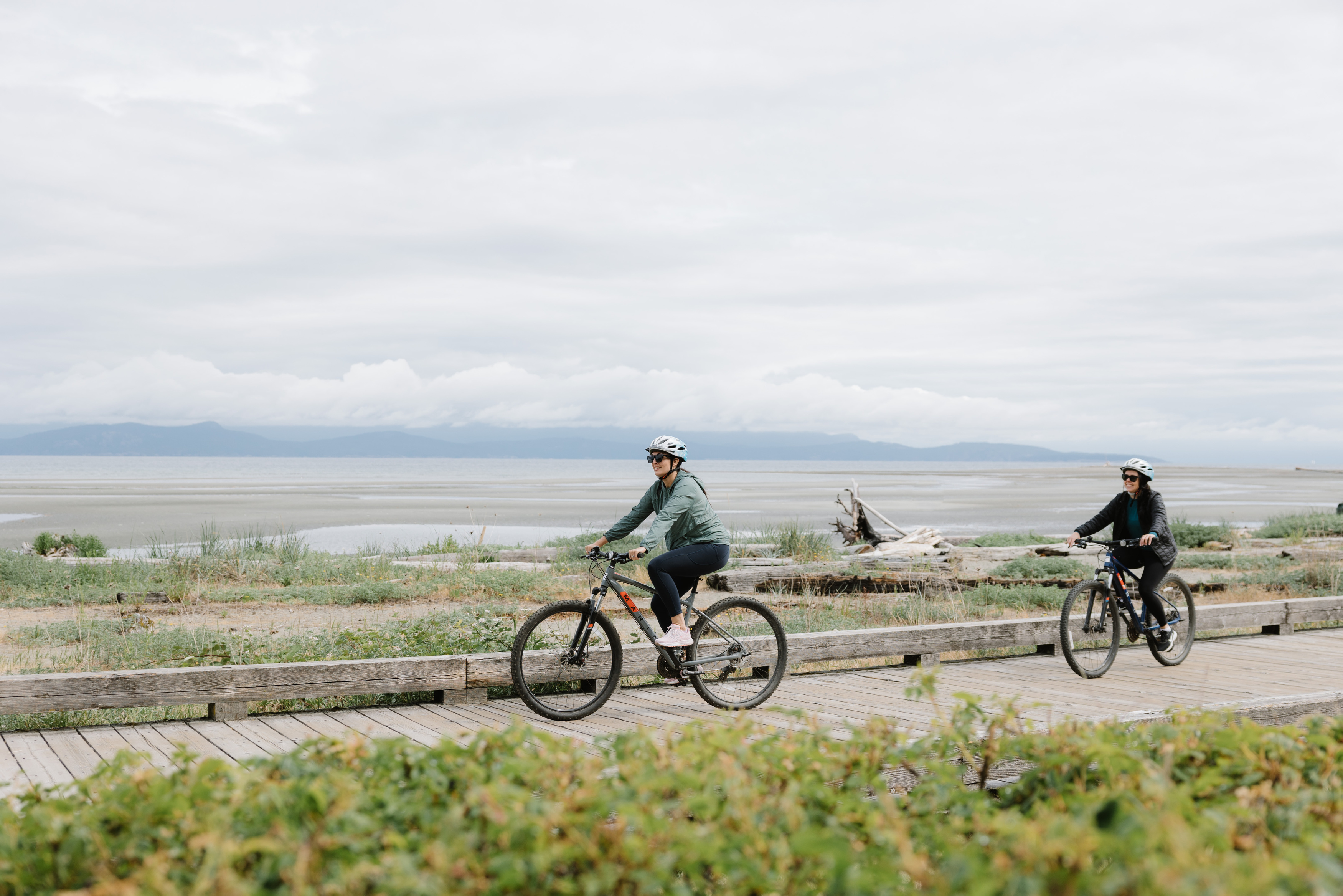 a couple of people riding bikes on a boardwalk